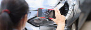 Agent takes smartphone photo of damage to car after accident. Photo and video fixation for car insurance concept